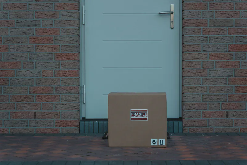 A lone cardboard parcel left on a doorstep in front of a closed front door